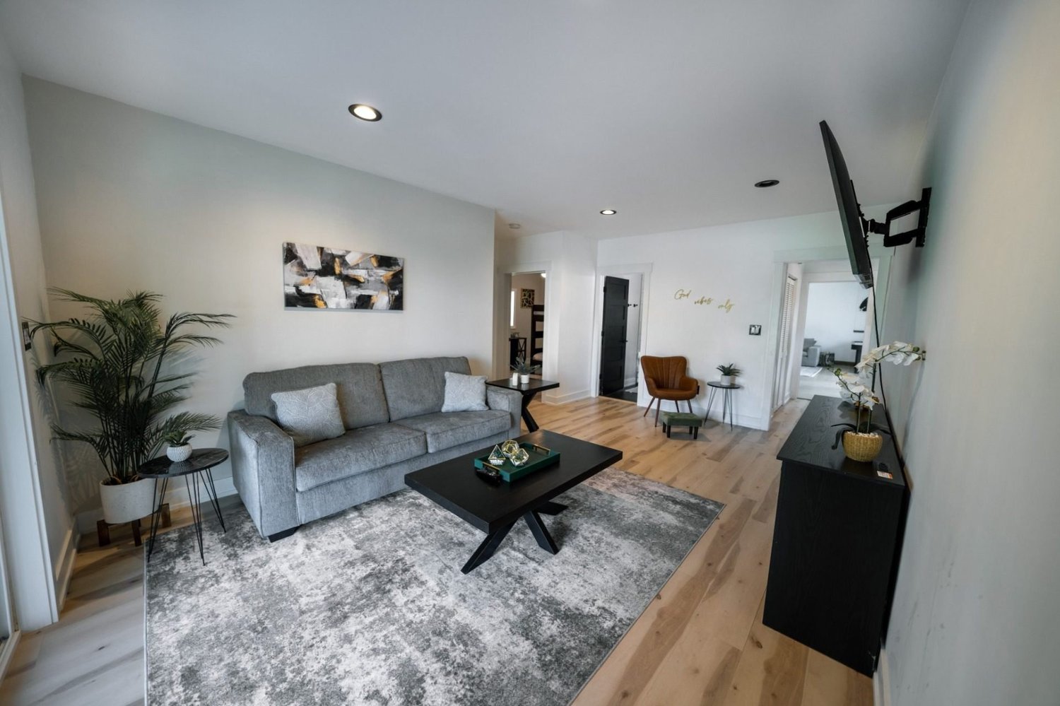 Living area with grey sofa, wood floors and abstract artwork
