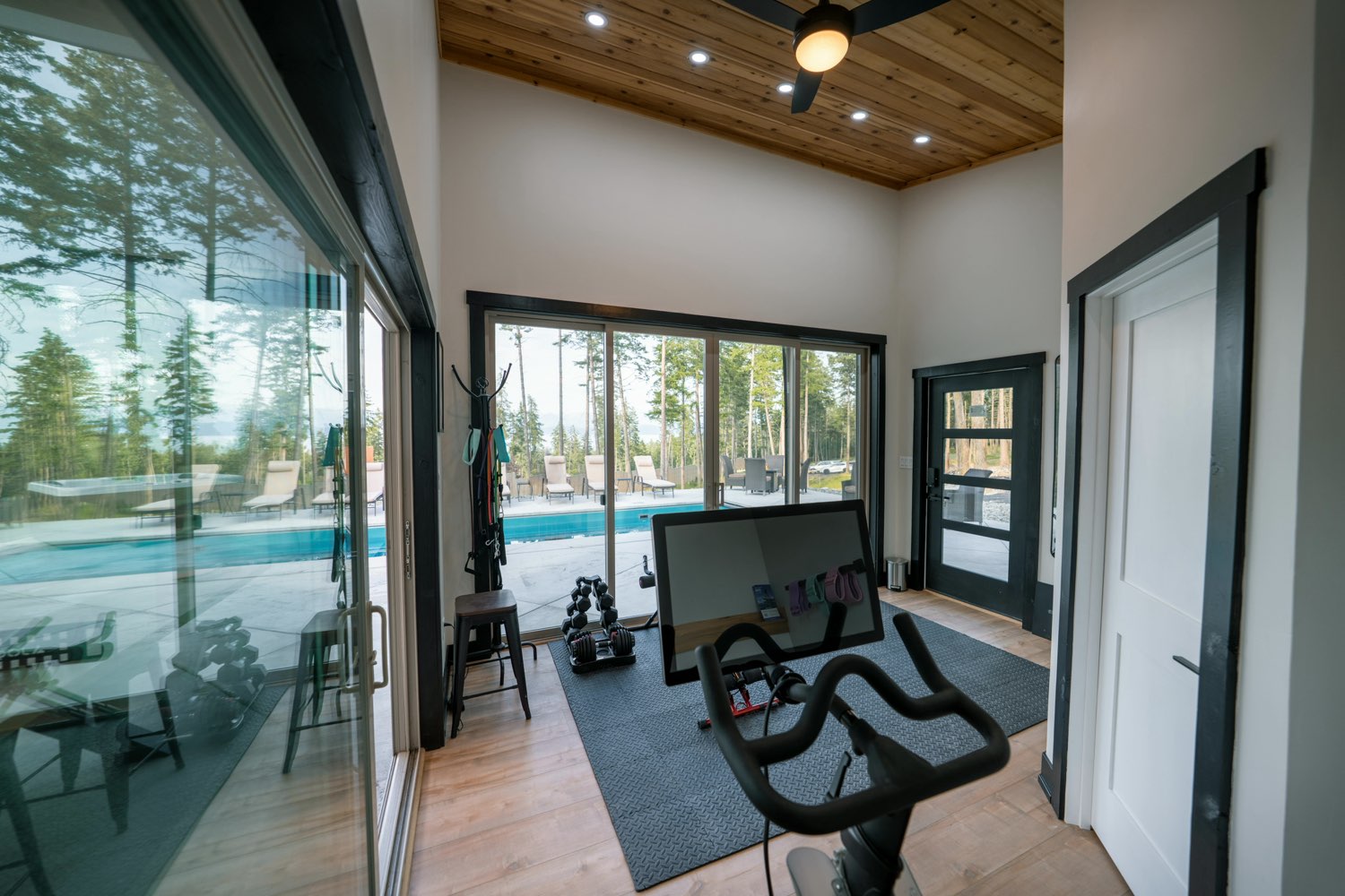 Gym in the estate pool house with an exercise bike, dumbbells and sliding glass doors onto the pool deck