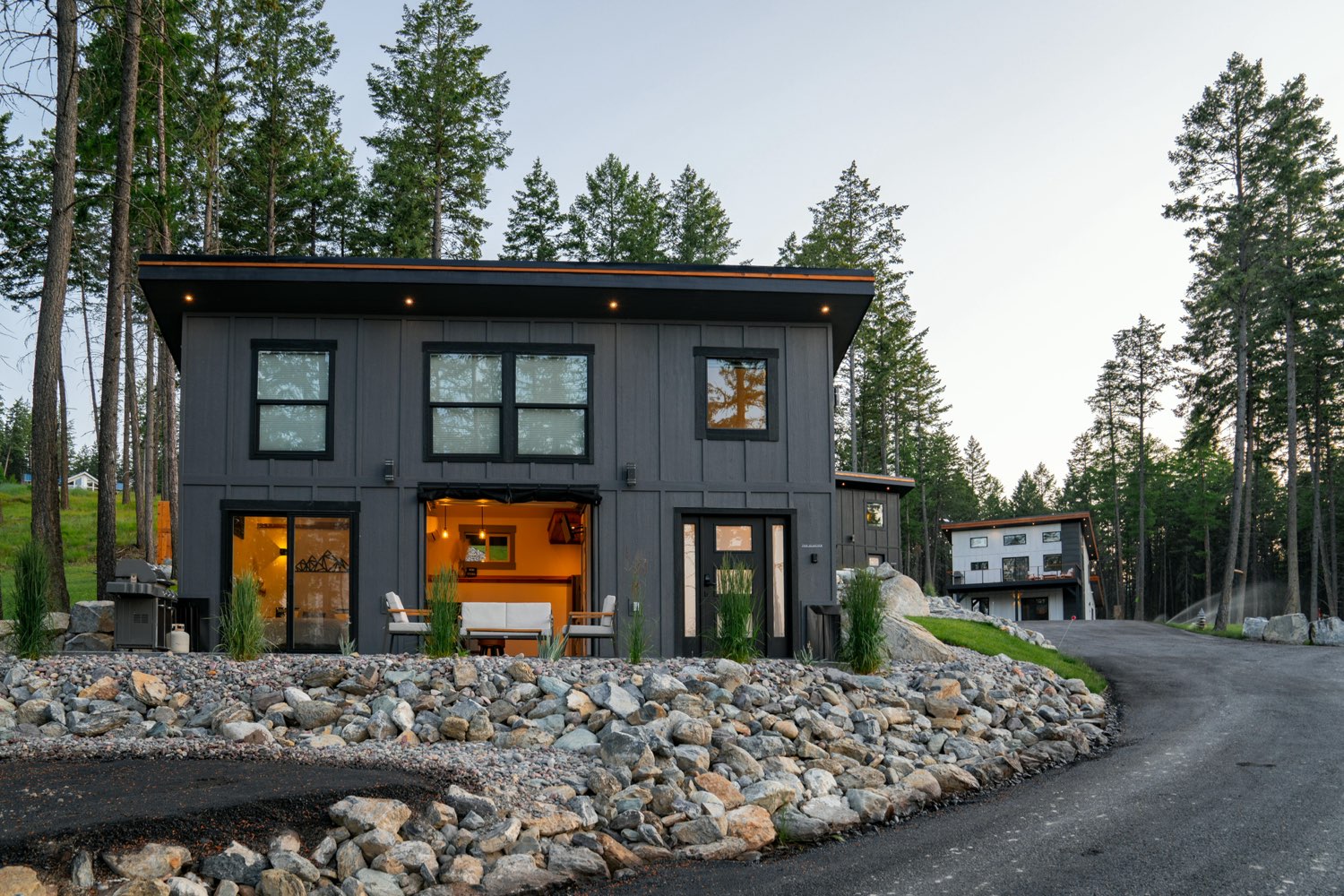 The Glacier House from the estate drive at dusk, with another of the homes among the pines beyond