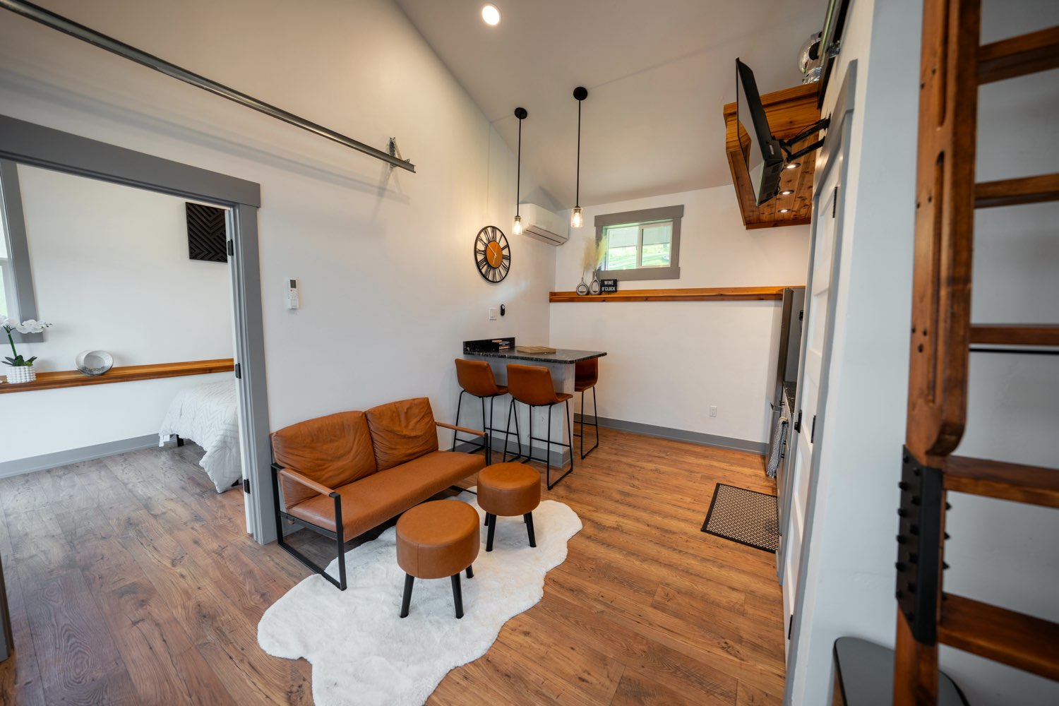 Living area at The Glacier House with a cognac leather loveseat, bar seating and the ladder up to the loft