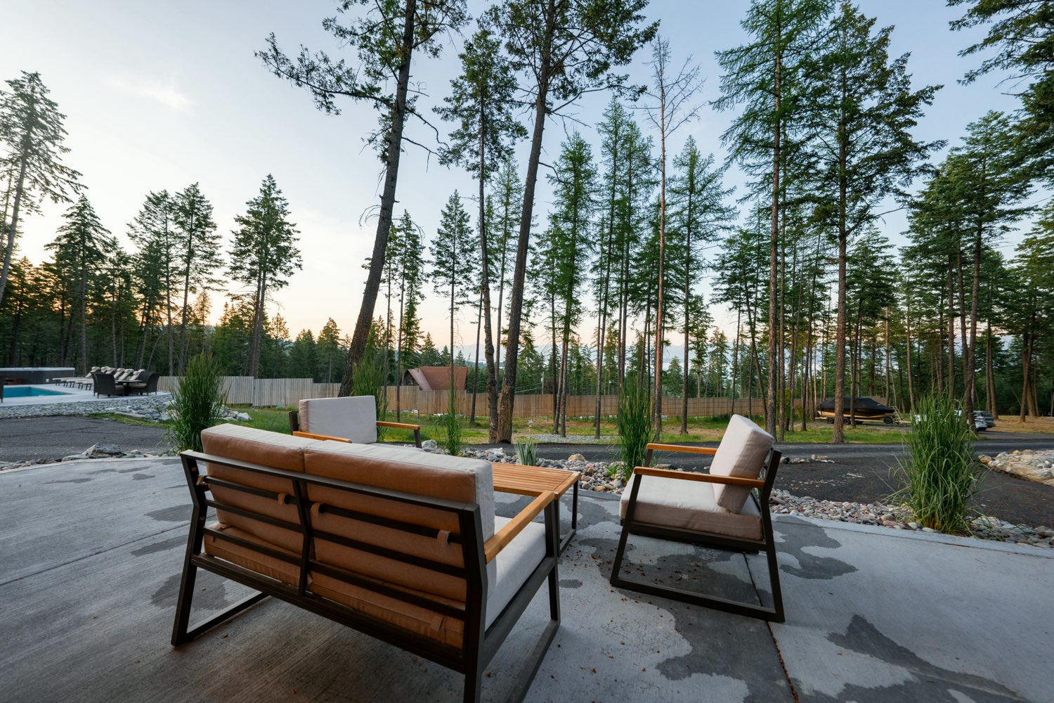 Patio seating at The Glacier House looking through the pines to the estate pool at dusk