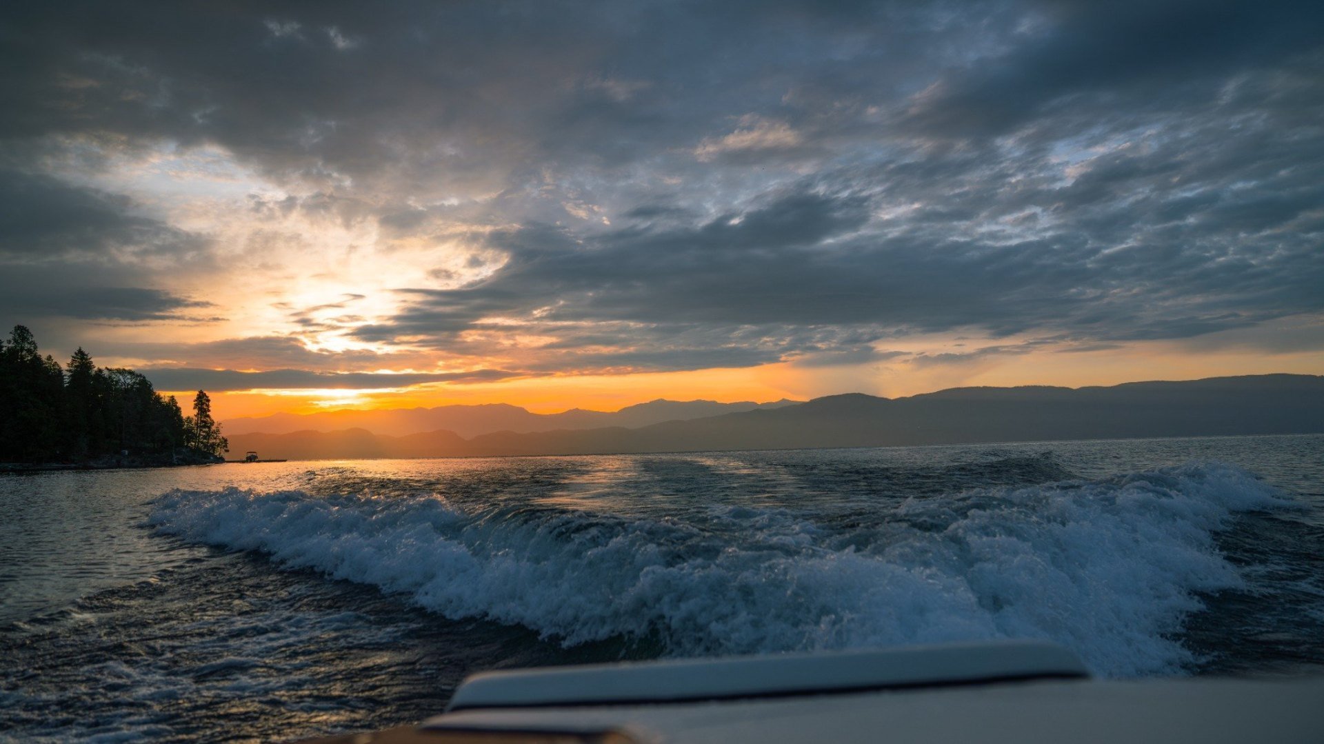 Boat wake catching the last light on Flathead Lake at sunset