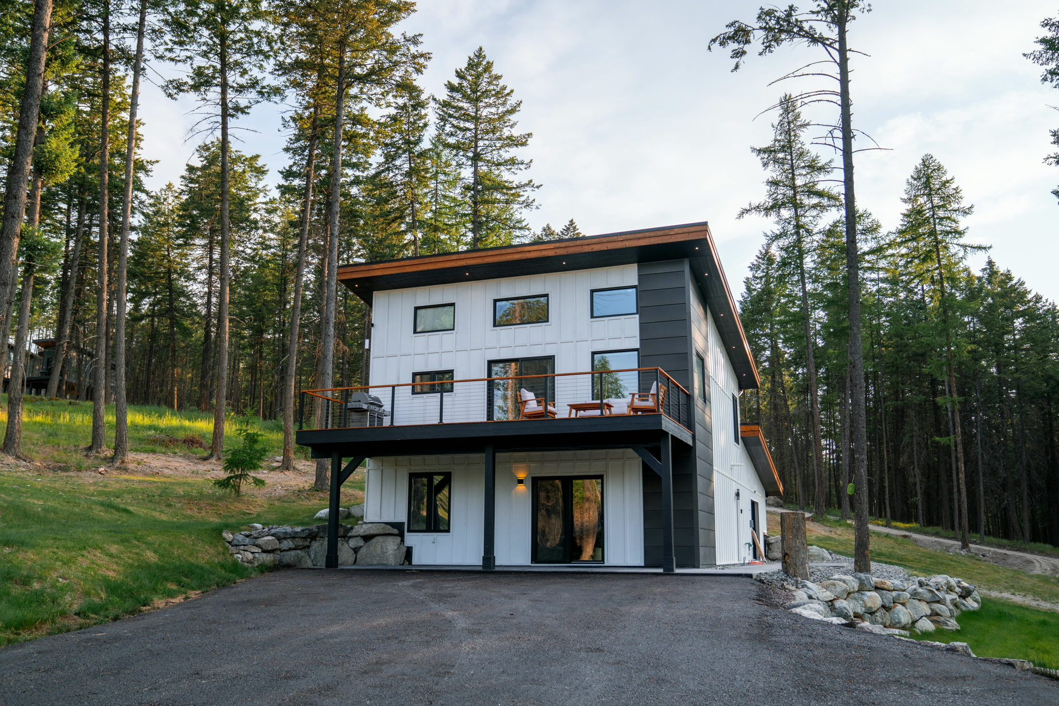 The Swan House, a three-story board-and-batten home with an upper deck, above the estate drive
