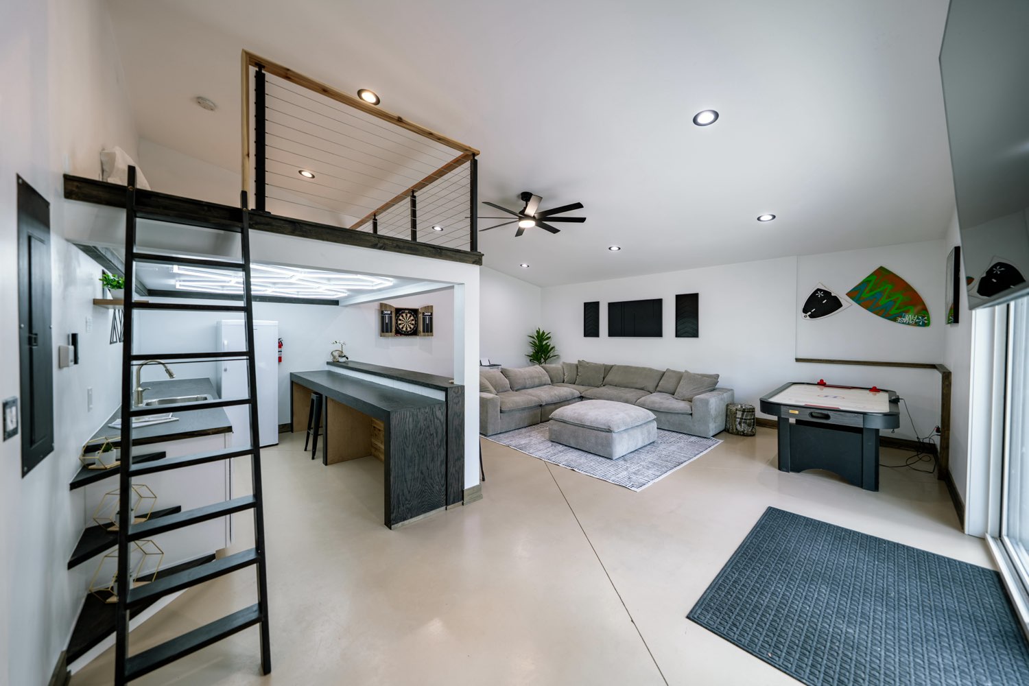 Game room at The Swan House with a sectional, an air hockey table, a dartboard, a wet bar and a ladder to the loft above