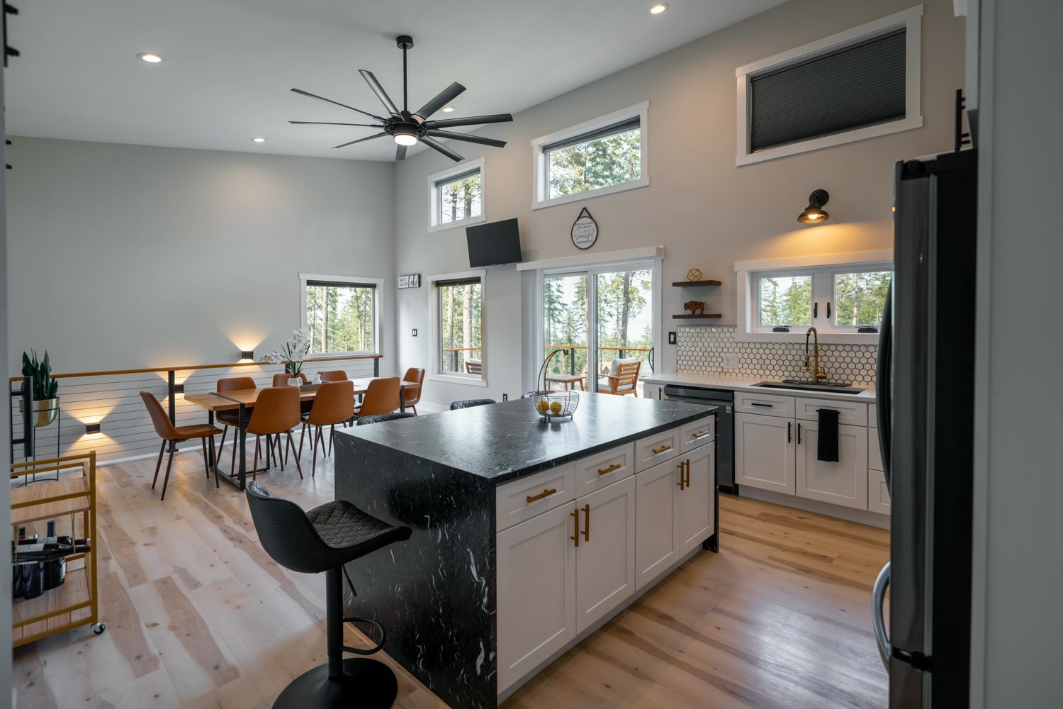 Kitchen and dining at The Swan House with a black stone island, white cabinetry and a long table under clerestory windows